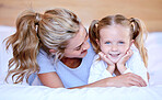 Happy caucasian mother and daughter lying on a bed at home. Cheerful woman with cute little girl enjoying a cosy and lazy relaxing day together. Loving parent bonding and sharing quality time with kid