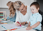 Family learning together at home. Mother helping son with homework during quarantine. Little boy drawing and having fun getting a distance education.