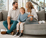 Happy caucasian family of three looking relaxed while sitting and bonding on the sofa together. Adorable little blonde boy chilling on a couch with his loving parents while chilling with them 