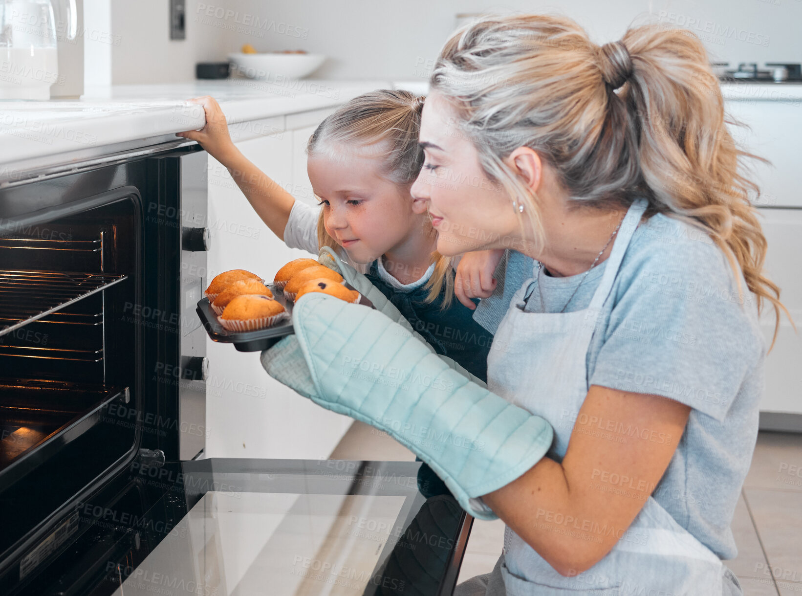 Buy stock photo Mom, oven and daughter in kitchen, smell and teaching of child of baking, recipe and muffins in home. Happy, girl and woman with gloves, smile and family with dessert, cupcakes and love for food