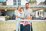 Portrait of happy caucasian family holding for sale and sold sign while relocating and moving in new house. Smiling parents and kids securing homeowner loan for property real estate and home purchase