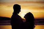 Silhouette couple enjoying romantic moment standing face to face looking into eyes at sunset. Unknown boyfriend and girlfriend feeling in love while bonding at the beach