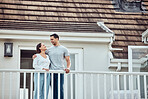 Happy young mixed race couple standing on the balcony at their new home. Hispanic couple looking into each others eyes. Loving husband and wife standing outside getting fresh air