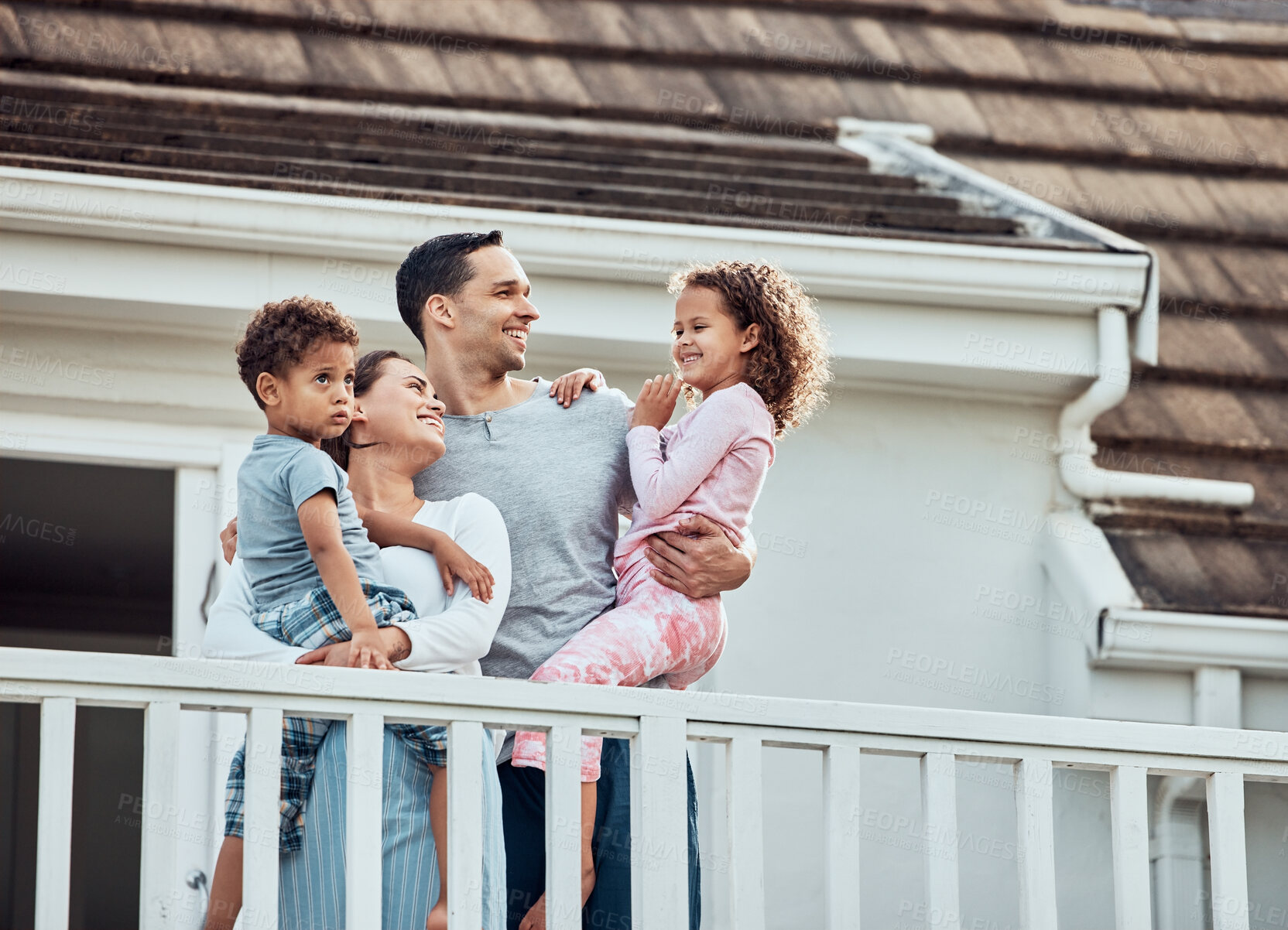 Buy stock photo Happy, family and outdoor on balcony with love, affection and bonding with hug for care or connection. Mother, father and children by modern house with pajamas in morning, together and support.