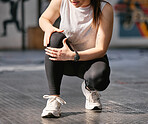 Closeup of one caucasian woman holding her sore knee while exercising in a gym. Female athlete suffering with painful leg injury from fractured joint and inflamed muscles during workout. Struggling with stiff body cramps causing discomfort and strain