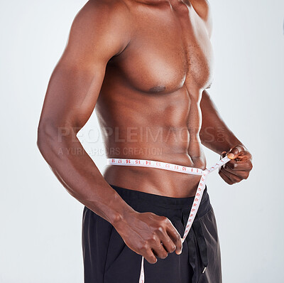 Buy stock photo Man, size and waist with measuring tape for weightloss, diet or slimline on a gray studio background. Muscular African, male person or model with body measurement for wasitline, fitness or BMI