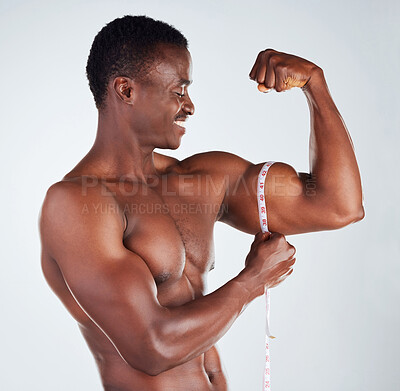 Buy stock photo Happy, black man and flex with measuring tape for bicep, muscle gain or strength on a gray studio background. Muscular African, male person or young model with smile for arm scale, fitness or size