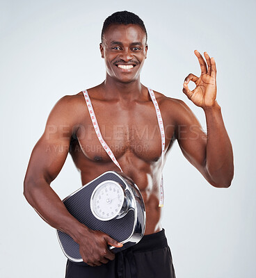 Buy stock photo Measuring tape, scale and black man with perfect gesture in studio with okay for bulking progress. Portrait, fitness and African male person with weight tracking tools for gym by white background.