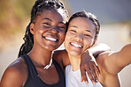 Two female athletes smiling and posing together while exercising outdoors. Two happy female friends in sportswear smiling and standing together while out for a run