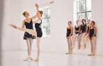 Young woman dance instructor teaching a ballet class to a group of a children in her studio. Ballerina teacher working with girl students, preparing for their recital, performance or upcoming show