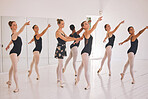 Young woman dance instructor teaching a ballet class to a group of a children in her studio. Ballerina teacher working with girl students, preparing for their recital, performance or upcoming show