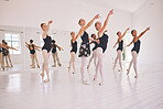 Young woman dance instructor teaching a ballet class to a group of a children in her studio. Ballerina teacher working with girl students, preparing for their recital, performance or upcoming show