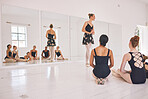 Young woman dance instructor teaching a ballet class to a group of a children in her studio. Ballerina teacher working with girl students, preparing for their recital, performance or upcoming show