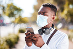 Unrecognizable black man wearing a mask to protect himself from the corona virus pandemic while wearing earphones and texting on a cellphone. Businessman walking to a an interview using gps on a phone