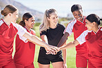 Female only soccer team joining hands in a huddle in unity, support and trust before a match or competition. Happy group or squad of women's football players on a field standing in a circle