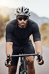 One athletic young man cycling outside. Sporty fit male wearing helmet and glasses while riding a bike on a road along the mountain for exercise. Endurance and cardio during a workout and training