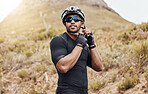 One fit and active indian man wearing sunglasses and adjusting his helmet to cycle for an outdoor workout. Serious mixed race athlete getting ready to exercise in nature. Focused on health and cardio