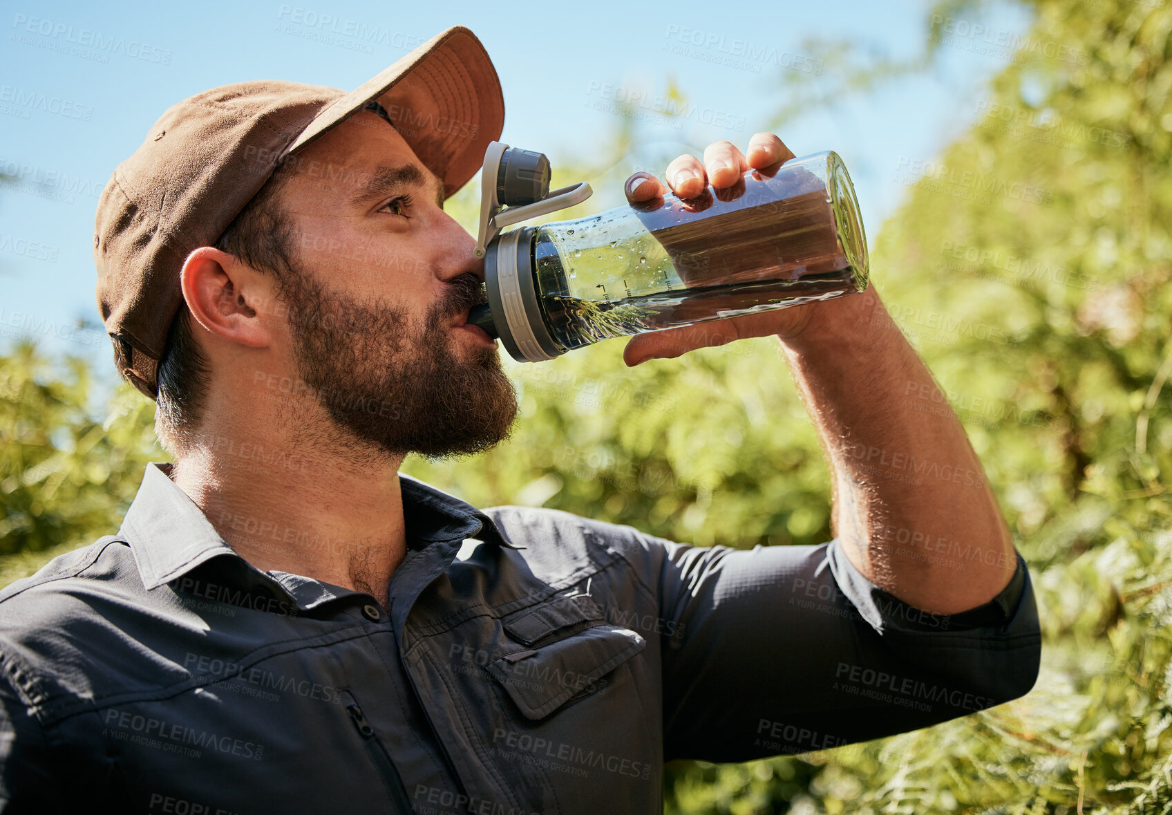 Buy stock photo Trekking, man and drinking water in forest outdoor on vacation, holiday or travel on adventure. Hiking, nature or thirsty person with bottle for refreshment, health or hydration on break in woods