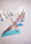 Group of women in yoga class together. Young women in side plank on yoga mats. Group of strong women balance in pilates class. Dedicated women balance side plank in yoga class