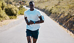 One handsome young african american athlete listening to music while out for a jog in nature. Dedicated black man working out alone outside. His fitness routine includes running to increase endurance