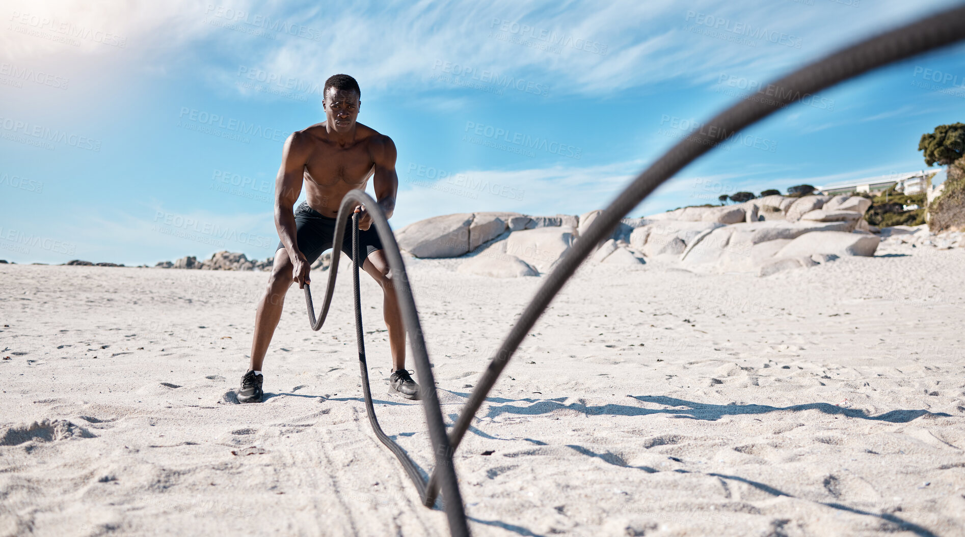 Buy stock photo Fitness, man and battle rope at beach for power, grip strength or intense cardio exercise. Sports, athlete and black person with full body workout for performance, muscle endurance or arm training