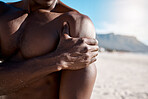 Closeup shot of an african american muscular athletic man holding his shoulder in pain. Black unrecognizable male suffering from arthritis in his arm. Suffering from a hurting, stiff, injured joint