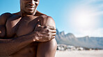 Closeup shot of an african american muscular athletic man holding his shoulder in pain. Black unrecognizable male suffering from arthritis in his arm. Suffering from a hurting, stiff, injured joint