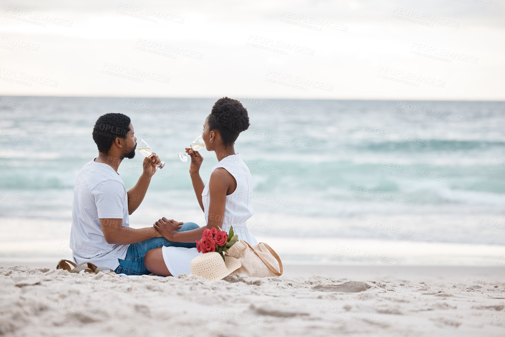 Buy stock photo Black couple, drink and relax on sand by beach for romantic date on vacation, anniversary getaway and bonding. Man, woman and together with white wine, ocean escape and commitment for love connection