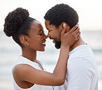 Cheerful african American couple spending a day at the sea together. Content boyfriend and girlfriend holding each other lovingly on the beach. Caring husband and wife bonding on the seashore