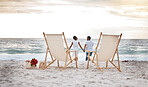 Rearview of a joyful african american couple spending a day at the sea together. Happy boyfriend and girlfriend holding hands while walking on the beach. Caring husband and wife bonding on the seashore