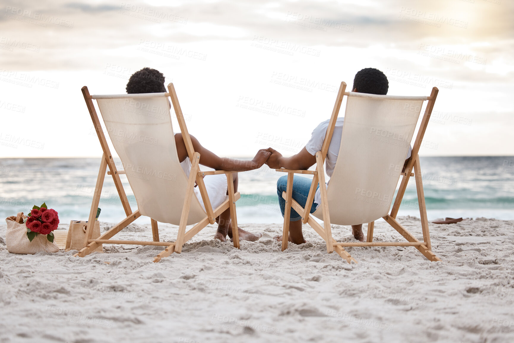 Buy stock photo Sunset, black couple and view with beach chair, holding hands or celebrating for anniversary. Vacation, picnic and people travel for marriage on honeymoon, summer holiday and happy bonding in Miami