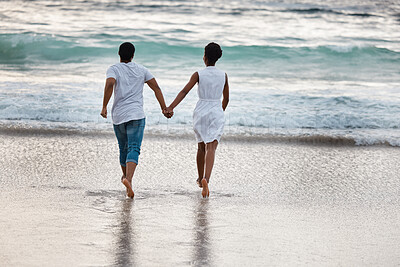 Buy stock photo Sunset, black couple and waves with splash, holding hands or celebrating for anniversary. Vacation, play and people travel for marriage on honeymoon, summer holiday and happy bonding in Miami