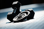 Closeup of a group of gym weights on the floor in an empty health and sports club. Macro view of dumbbells barbell weights in a dark exercise room. Lift weight for body strength, muscles and fitness