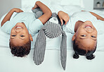 Adorable little sibling brother and sister lying upside down over the edge of a bed with a stuffed animal bunny. Cute little girl and boy having fun together at home in the morning