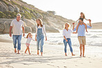 Multi generation family holding hands and walking along the beach together. Caucasian family with two children, two parents and grandparents enjoying summer vacation