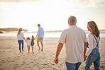 Rear view of Multi generation family holding hands and walking along the beach together. Caucasian family with two children, two parents and grandparents enjoying summer vacation