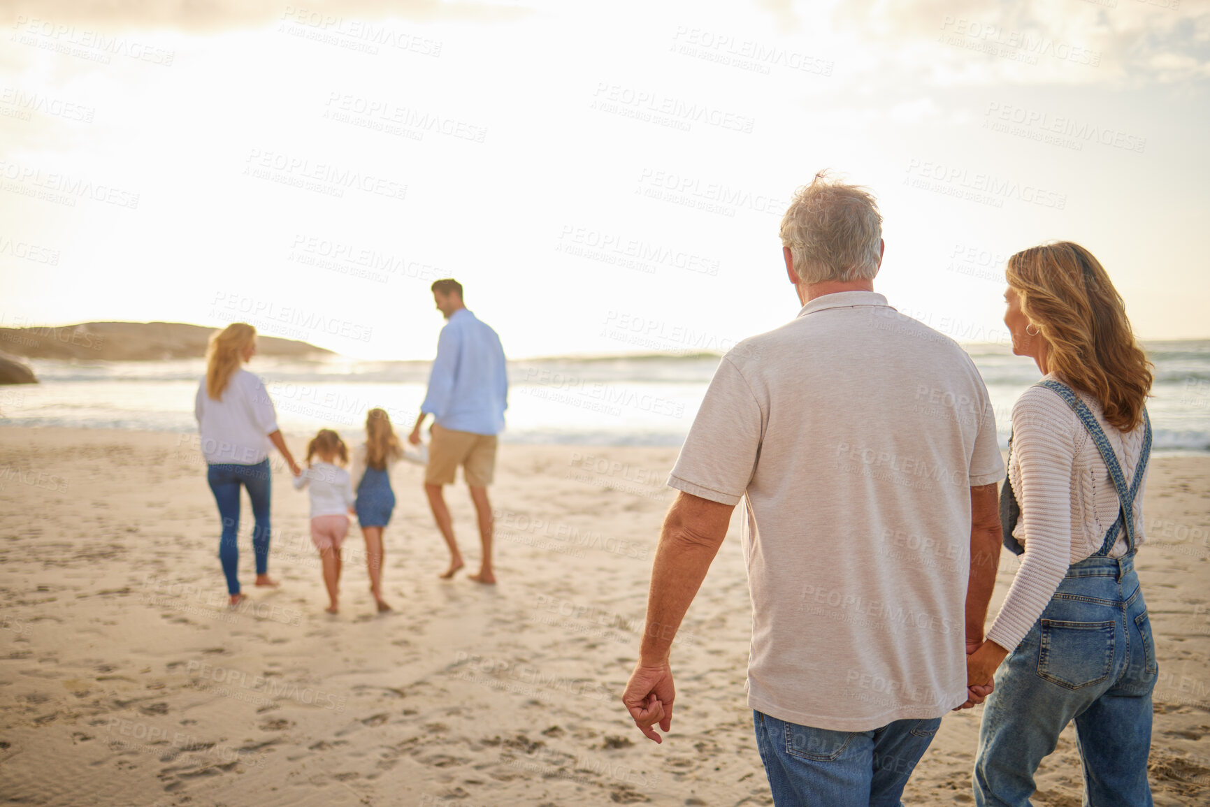 Buy stock photo People, family and generations with walking in beach for bonding, break and holiday in Bali. Parents, grandparents and kids in ocean on sunset for vacation, adventure and journey to relax and fun