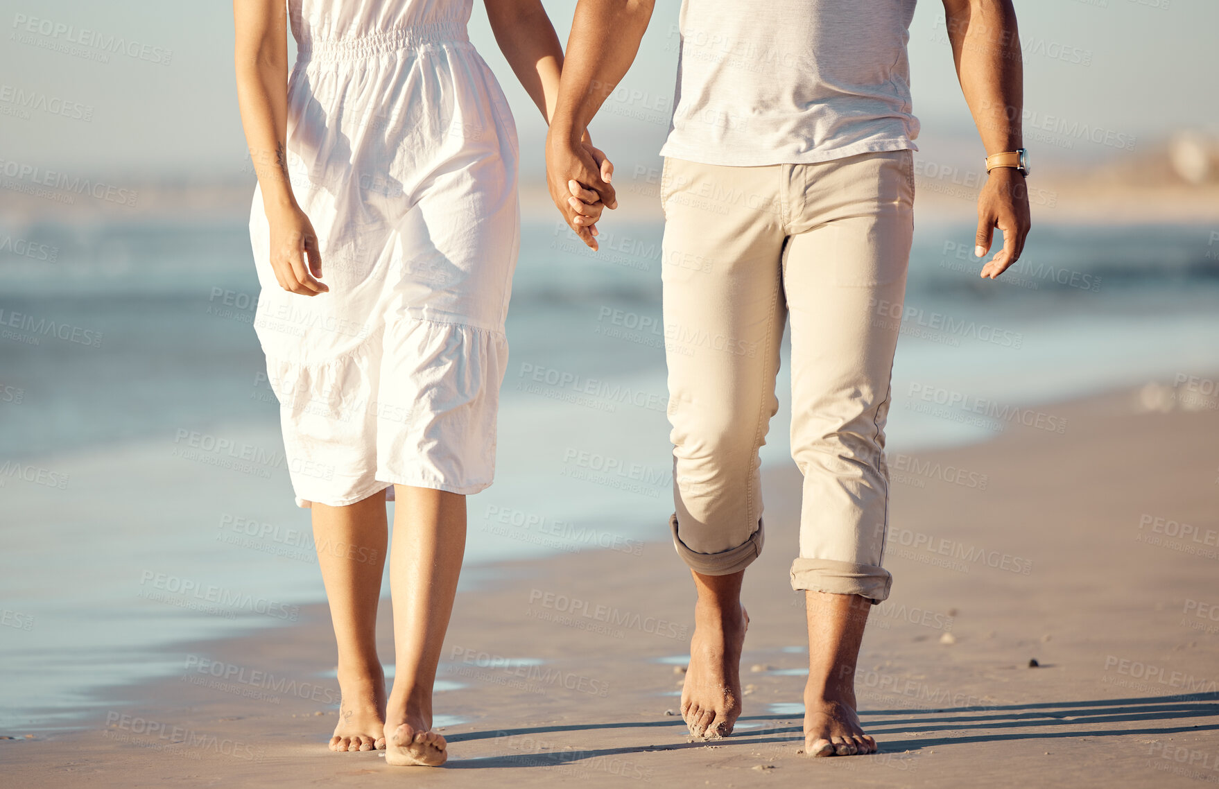 Buy stock photo Couple, walking and holding hands on beach with love for travel journey, care and bonding on marriage date by ocean. Feet, woman and man with support, trust and morning on vacation for peace outdoor