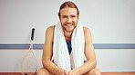 Portrait of a squash player with his racket. Caucasian man sitting in a gym locker room relaxing. Fit, young athlete taking a break before his match. Happy healthy player sitting in his gym