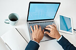 Closeup of a mixed race businessman typing an email on a laptop alone at work from above. One hispanic male businessperson working on a laptop in an office at work