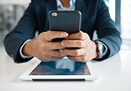 Closeup of a mixed race businessman holding and texting on a phone alone at work. One hispanic male businessperson working on a cellphone in an office at work
