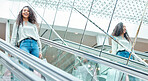 Portrait beautiful mixed race woman standing on an escalator while shopping in a mall. Young hispanic woman carrying bags, spending money, looking for sales and getting in some good retail therapy