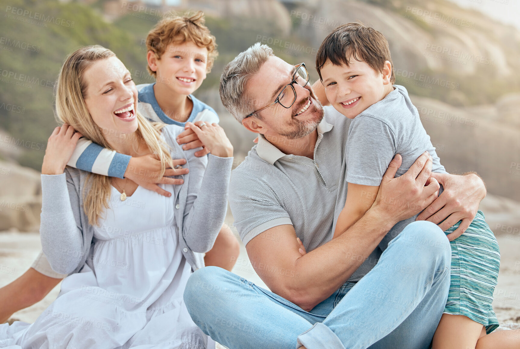 Buy stock photo Parents, kids and hug at beach with portrait, smile and bonding with love on vacation in summer. Father, mother and boy children on holiday for connection, embrace and family on ground in sunshine