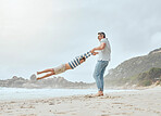 Happy caucasian father swinging and spinning his cute son in circles by the arms at the beach. Playful kid having fun while bonding with dad on sunny summer vacation outdoors