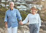 Happy and loving senior caucasian couple enjoying a romantic walk at the beach together on a sunny day. Cheerful affectionate husband and wife holding hands while bonding on vacation and retirement outdoors