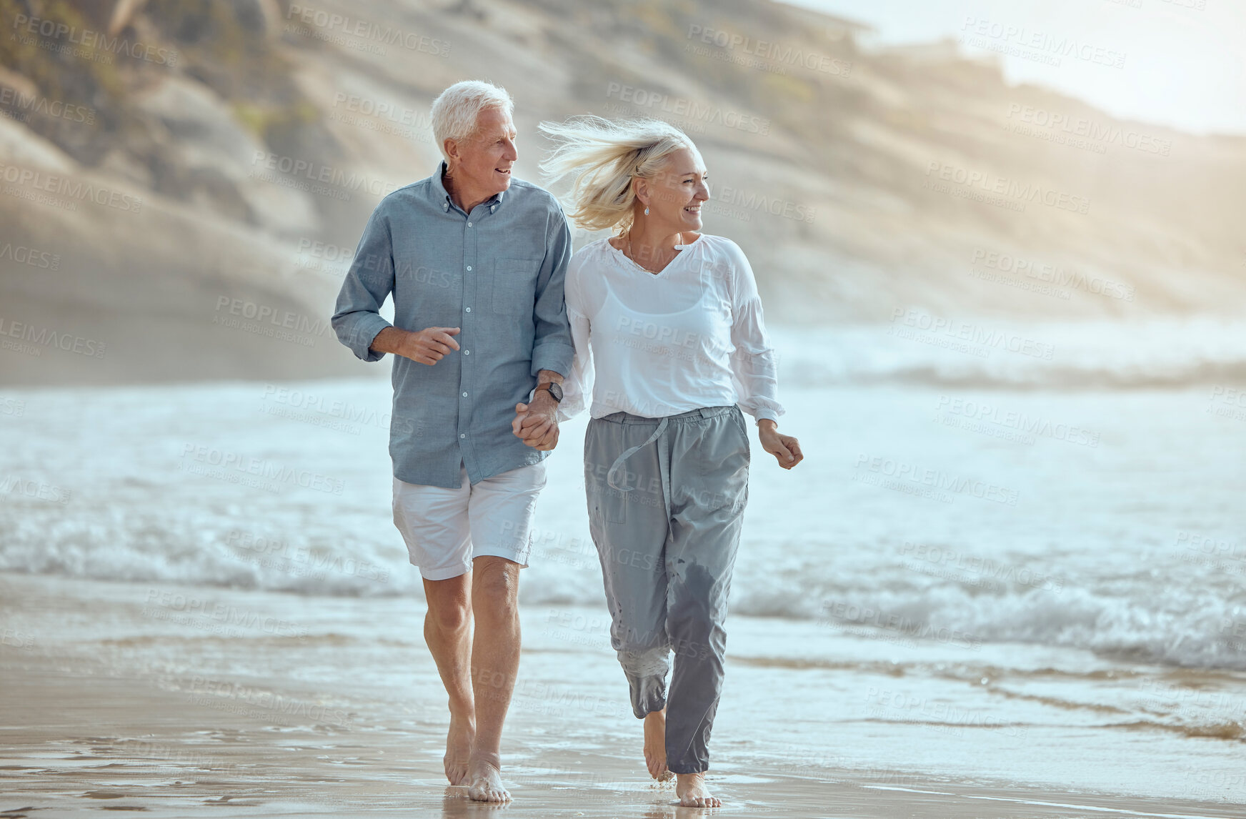 Buy stock photo Mature, couple and running on beach with love on retirement vacation, romance and together with fun or freedom. Man, woman and holding hands by ocean on holiday, happy and bonding with energy.