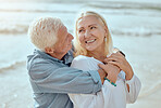 A happy mature caucasian couple enjoying fresh air on vacation at the beach. Smiling retired couple hugging and embracing while bonding outside together