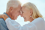 A happy mature caucasian couple enjoying fresh air on vacation at the beach. Smiling retired couple hugging and embracing while bonding outside together