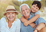 Happy caucasian grandparents sitting with grandson on a beach. Adorable, happy, child bonding with grandmother and grandfather in a garden or park outside. Boy with foster parents