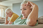 Unhappy elderly couple sitting on a sofa together after arguing. Senior caucasian man and woman looking stressed and ready for divorce